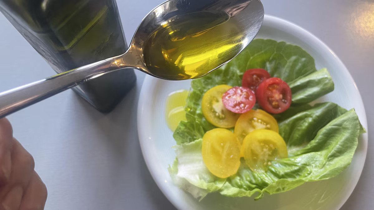 Ein Löffel Leinöl wird über einen Salat gegeben